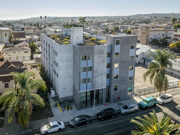 San Pedro apartment for rent - A modern concrete building with a parking lot in front.