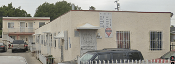 Los Angeles apartment for rent - A white building with a sign on it and a car parked in front.