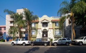 Los Angeles apartment for rent - A row of cars are parked in front of a building with palm trees.