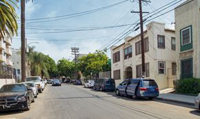 Los Angeles apartment for rent - A street with cars parked on both sides and a few moving cars.