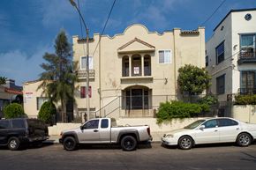 Los Angeles apartment for rent - A white pickup truck is parked in front of a tan building.