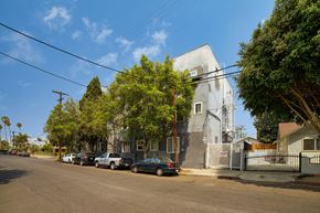 Los Angeles apartment for rent - A street with cars parked on the side and a house with a grey facade.