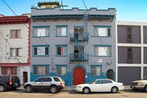 Los Angeles apartment for rent - A white car is parked in front of a blue building with a red door.
