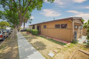 Los Angeles apartment for rent - A house with a brown exterior is surrounded by a fence and a tree.