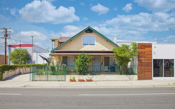 Signal Hill apartment for rent - A house with a green fence and a red awning is in front of a white building.