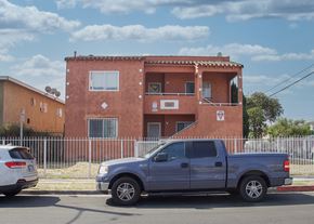 Los Angeles apartment for rent - A silver truck is parked in front of a red building.