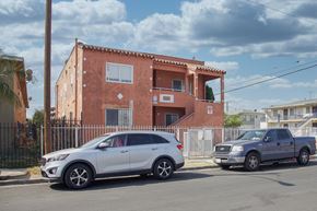 Los Angeles apartment for rent - A white car is parked in front of a red building.