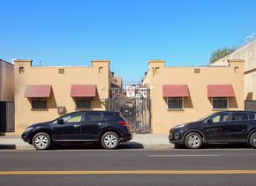 Los Angeles apartment for rent - Two black cars are parked in front of a building with red awnings.