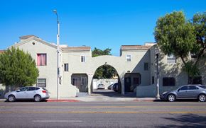 Los Angeles apartment for rent - A white building with a red door and a car parked in front.