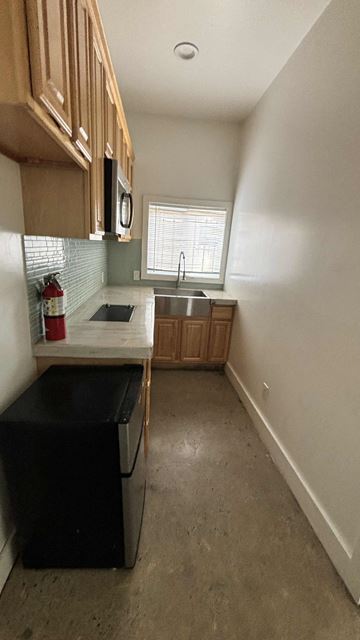 Los Angeles apartment for rent - A kitchen with a black fridge and wooden cabinets.