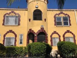 Los Angeles apartment for rent - A yellow building with arched windows and a black fence in front.