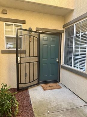 Oceanside townhouse for rent - A green door is closed with a gate in front of it.
