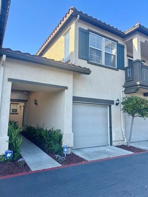 Oceanside townhouse for rent - A house with a garage door and a tree in front.