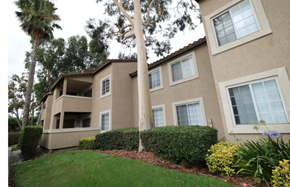 Ontario apartment for rent - A beige building with a red tile roof and a green lawn in front.