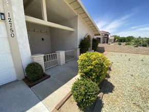 Victorville apartment for rent - A house numbered 12750 with a white garage door and a small garden in front.