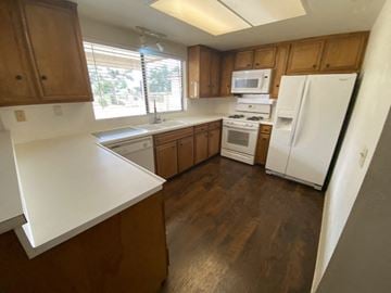 Victorville apartment for rent - A kitchen with wooden cabinets and white appliances.