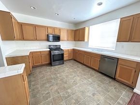Victorville house for rent - A kitchen with brown cabinets and a black stove top oven.
