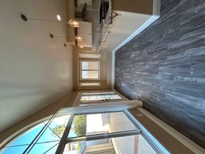 Corona house for rent - A long hallway with a stone wall on the right and a window on the left.