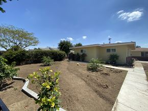 Ontario triplex for rent - A backyard with a dirt area and a concrete walkway.