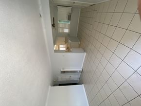 Ontario triplex for rent - A white tiled hallway with a staircase leading to a second floor.