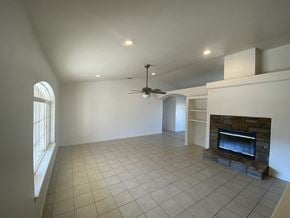 Hesperia house for rent - A living room with a fireplace and a ceiling fan.