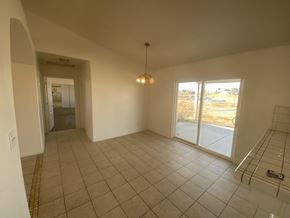 Hesperia house for rent - A large empty room with a tiled floor and a chandelier hanging from the ceiling.
