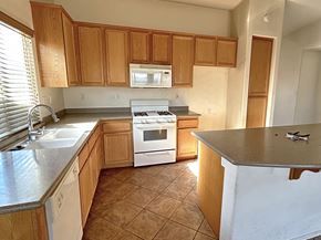 Victorville house for rent - A kitchen with wooden cabinets and a white stove top oven.