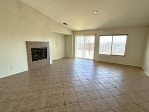 Victorville house for rent - A large empty room with a fireplace and tiled flooring.