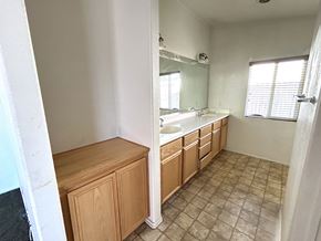 Victorville house for rent - A bathroom with a sink, mirror, and wooden cabinet.