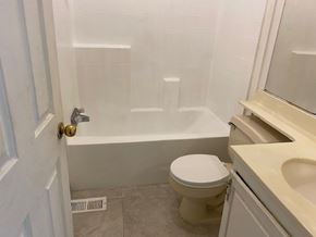 Adelanto house for rent - A white toilet sits next to a bathtub in a bathroom.