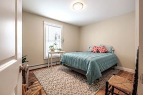 South Portland apartment for rent - A bedroom with a bed, a chair, and a table with a plant on it.