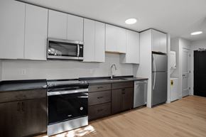 Biddeford apartment for rent - a kitchen with white cabinets and stainless steel appliances and a refrigerator