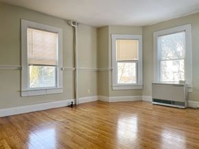 Portland apartment for rent - an empty living room with wood floors and three windows