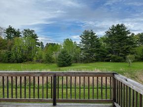Gorham apartment for rent - A wooden deck overlooks a grassy field and trees.