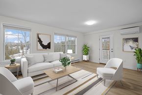 Scarborough apartment for rent - A living room with a white couch, a coffee table, and a large window with a view of the outdoors.