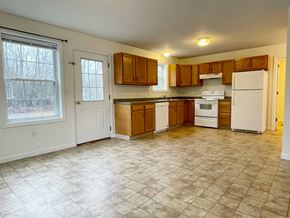 Buxton triplex for rent - A kitchen with white appliances and wooden cabinets.