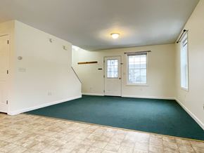 Buxton triplex for rent - A room with a green carpet and a window with blinds.
