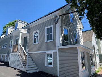 Portland apartment for rent - a gray house with white trim and stairs on a street