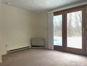 Gorham apartment for rent - an empty living room with sliding glass doors and a heater