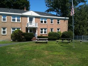 Portland apartment for rent - the front of a brick building with a picnic table and an flag
