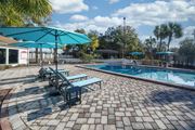 Jacksonville apartment for rent - A pool area with a blue umbrella and a brick patio. at Red Bay Apartment Complex, Jacksonville, FL, 32211