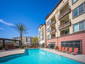 Tustin apartment for rent - a swimming pool with chairs around it and a building in the background