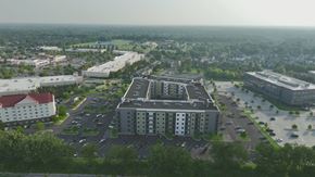 Louisville apartment for rent - A large grey building with a parking lot in front of it.