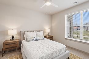 Bowling Green apartment for rent - A bedroom with a large bed, two lamps, and a window with blinds.