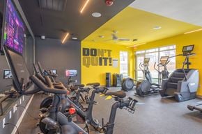 Louisville apartment for rent - A gym with exercise bikes and a yellow wall with the words "Don't Quit!" on it.