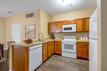 Louisville apartment for rent - A kitchen with wooden cabinets and white appliances.
