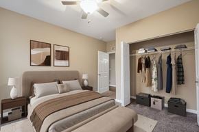 Louisville apartment for rent - A bedroom with a large bed and a closet with clothes hanging.