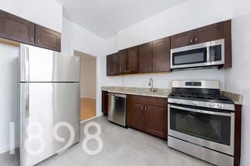 Woodside apartment for rent - A kitchen with a refrigerator, oven, and microwave.