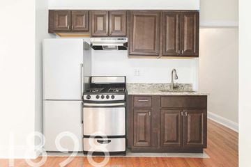 Sunnyside apartment for rent - A kitchen with a white refrigerator and stainless steel oven.