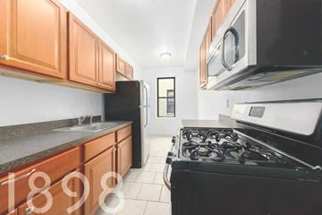 Sunnyside apartment for rent - A kitchen with black appliances and wooden cabinets.